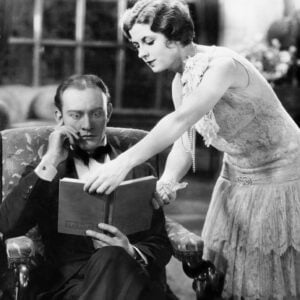 1920s pic of man and woman looking at book