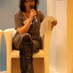 Debbie Young seated, speaking into a microphone, reading from a script