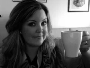 Photo of Catherine Ryan Howard raising a cup of coffee in a toast