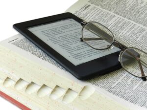 Pair of glasses on a Kindle and a print dictionary