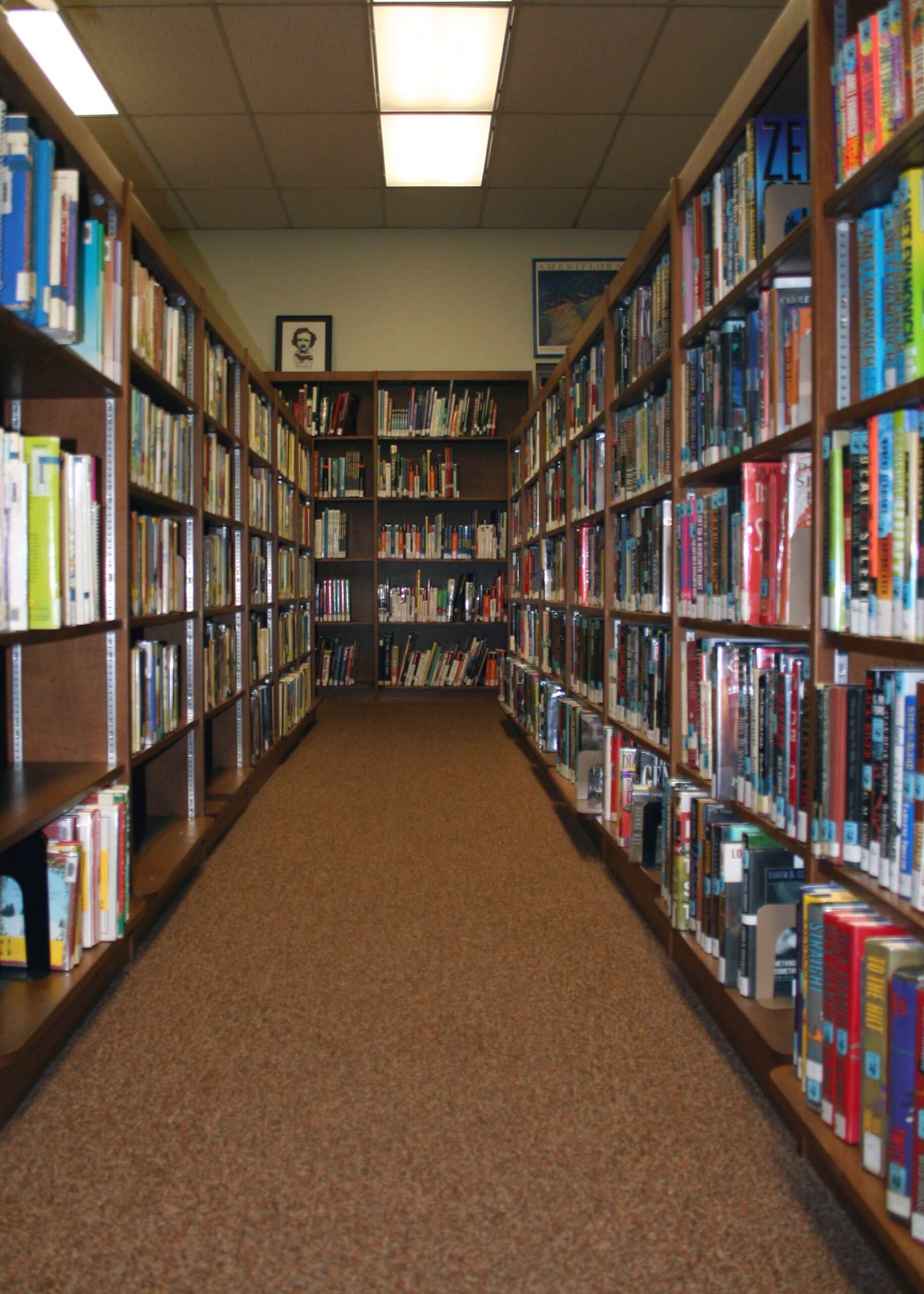 Photo Looking Down A Row Of Shelves In A Library