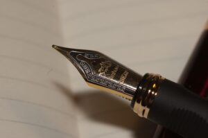Fountain pen nib poised over blank page