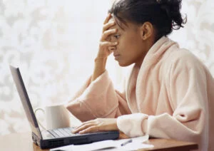 Woman at keyboard with despairing hand over face