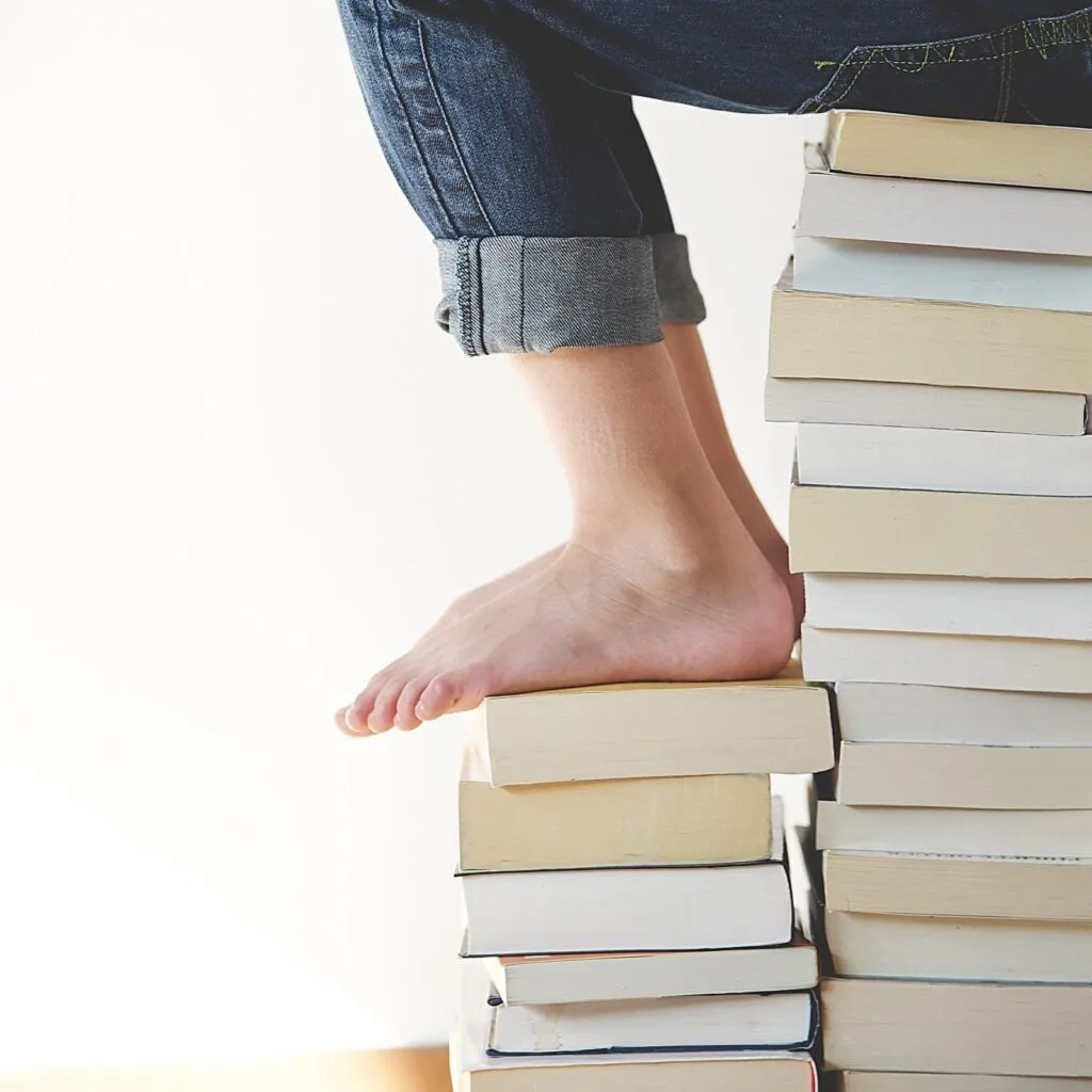Photo of someone sitting with their feet on a big stack of books