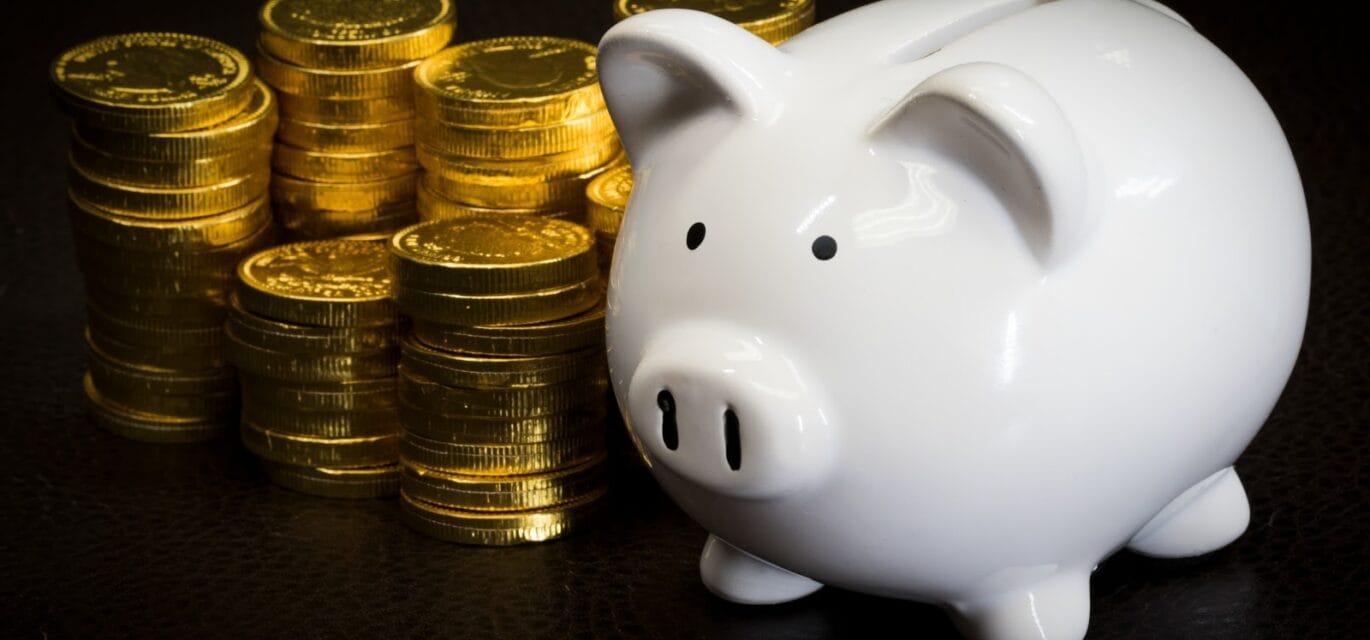 photo of a piggy bank with piles of gold coins