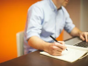 image of man writing a list at his desk