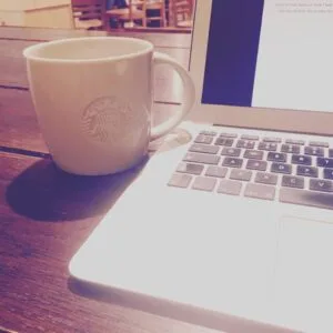 Coffee cup by laptop