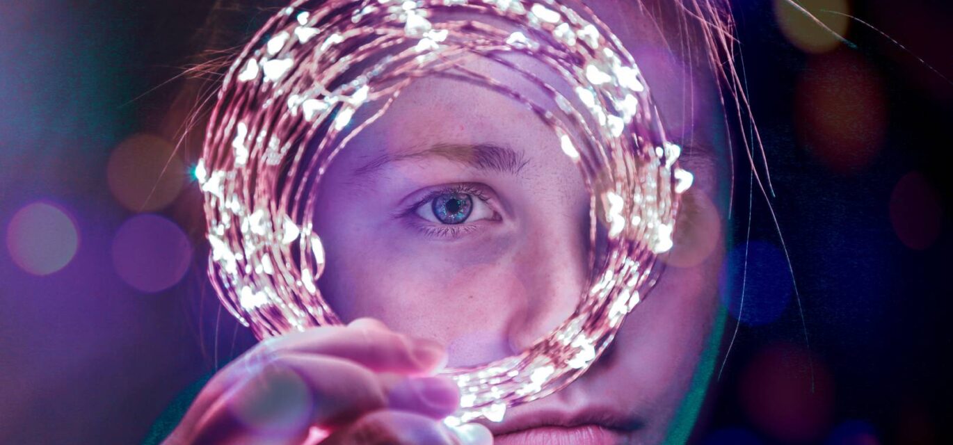 Photo of girl looking through circle of lights by Brendan Church via Unsplash.com