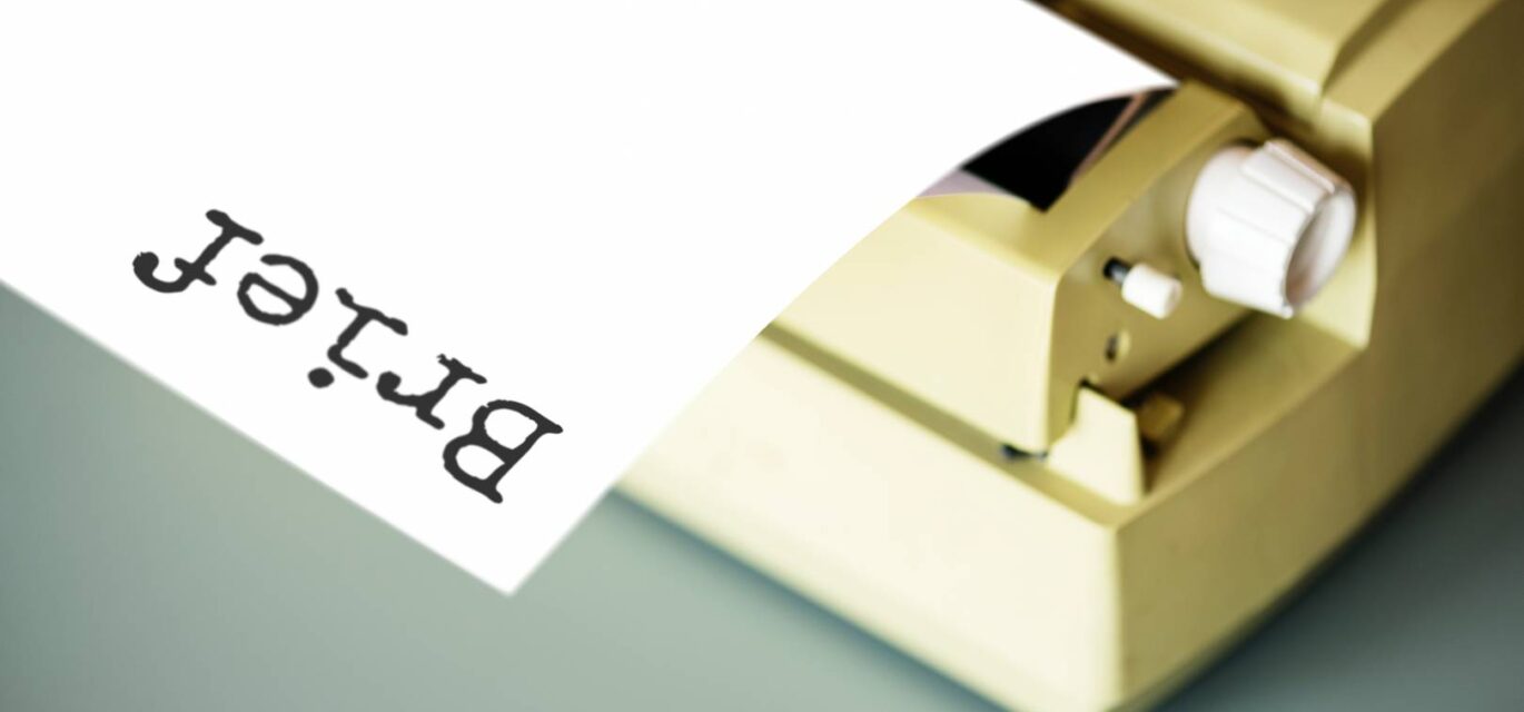 photo of typewriter with blank sheet of paper headed "Brief"