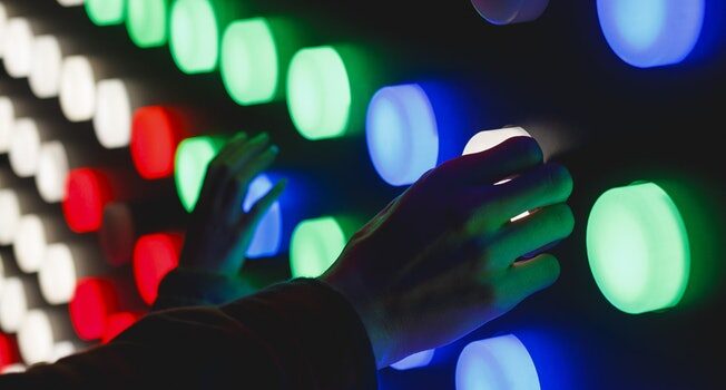 photo by Katya Austin on Unsplash of hands on different coloured lights looking like an experiment
