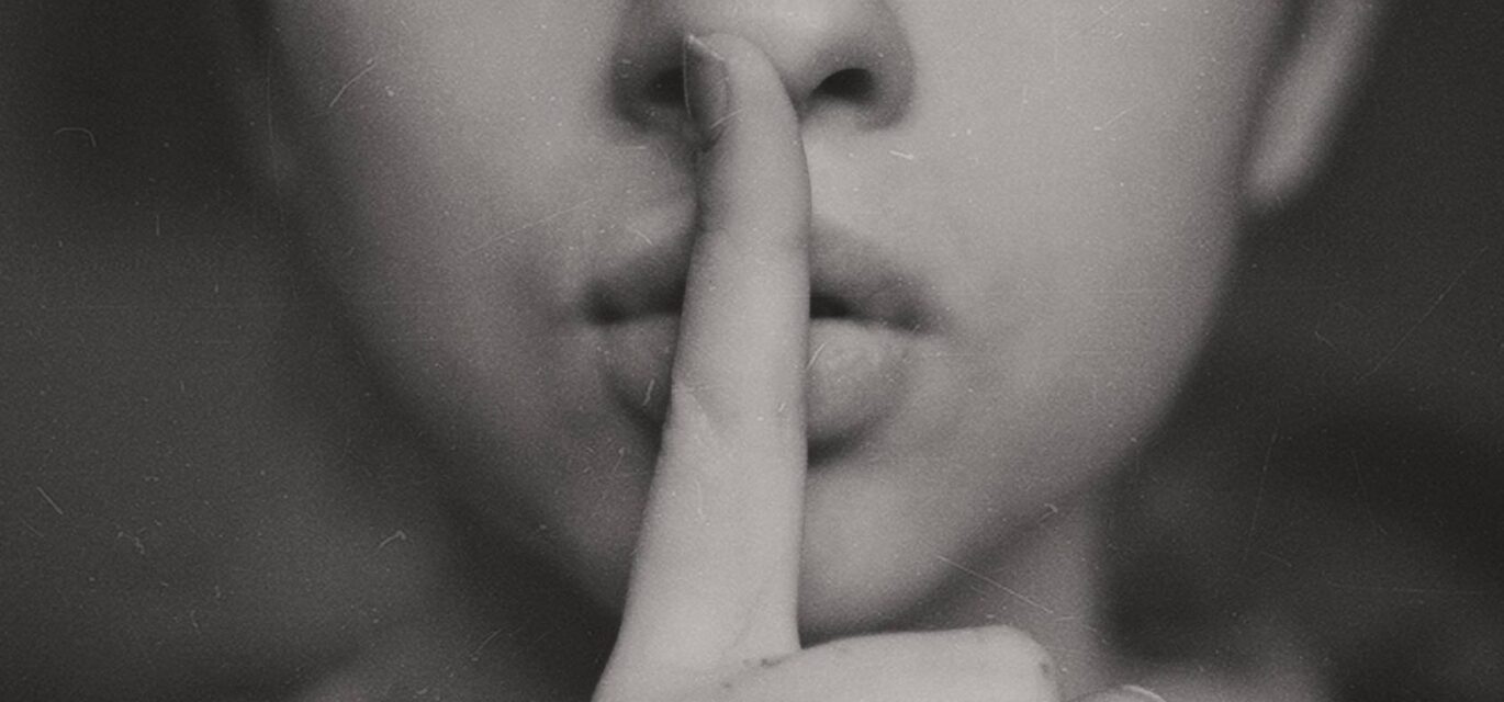 photo of someone with their finger to their lips in a shushing action