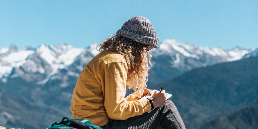Girl Sitting Writing On Mountain