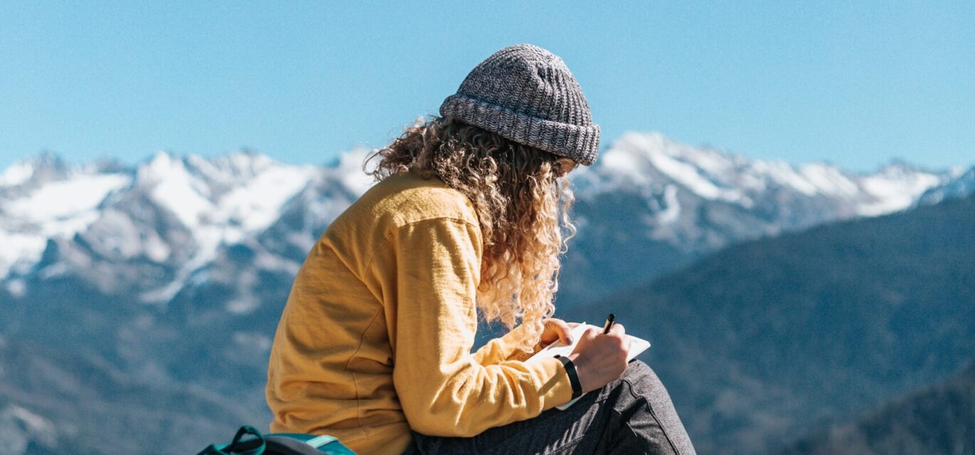 girl sitting writing on mountain