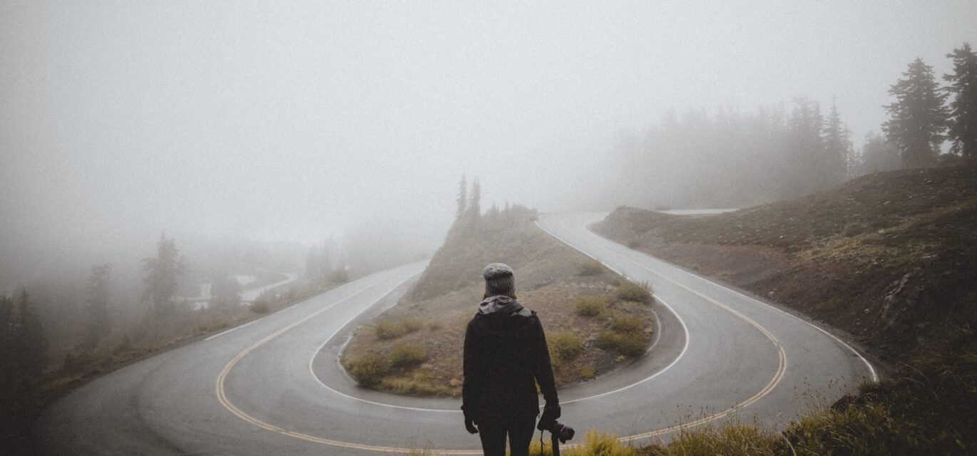 photo of u-bend in road and man looking at it to signify a turning point