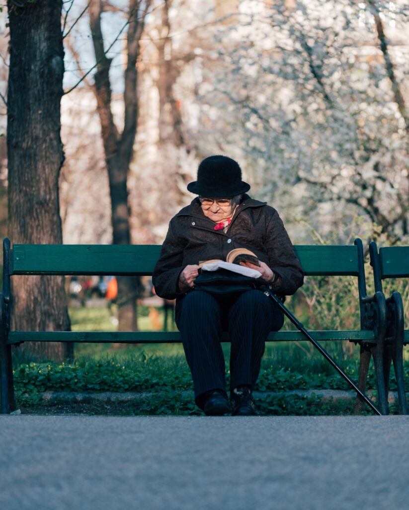 photo of old lady reading in the park