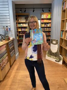 Karen holding a copy of her book in a store