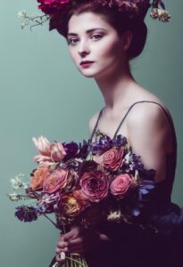 AI: woman holding a large bouquet of wilting flowers; muted colors, vintage