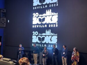 Final "Ask me anything" panel for 20books Seville. A number of speakers stood in front of a cinema screen displaying a 20books seville image.