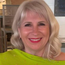 Smiling Woman With Blonde Hair In Green Top.