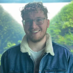 Smiling Man In Denim Jacket With Glasses.
