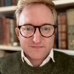 Man With Glasses And Green Sweater Indoors.